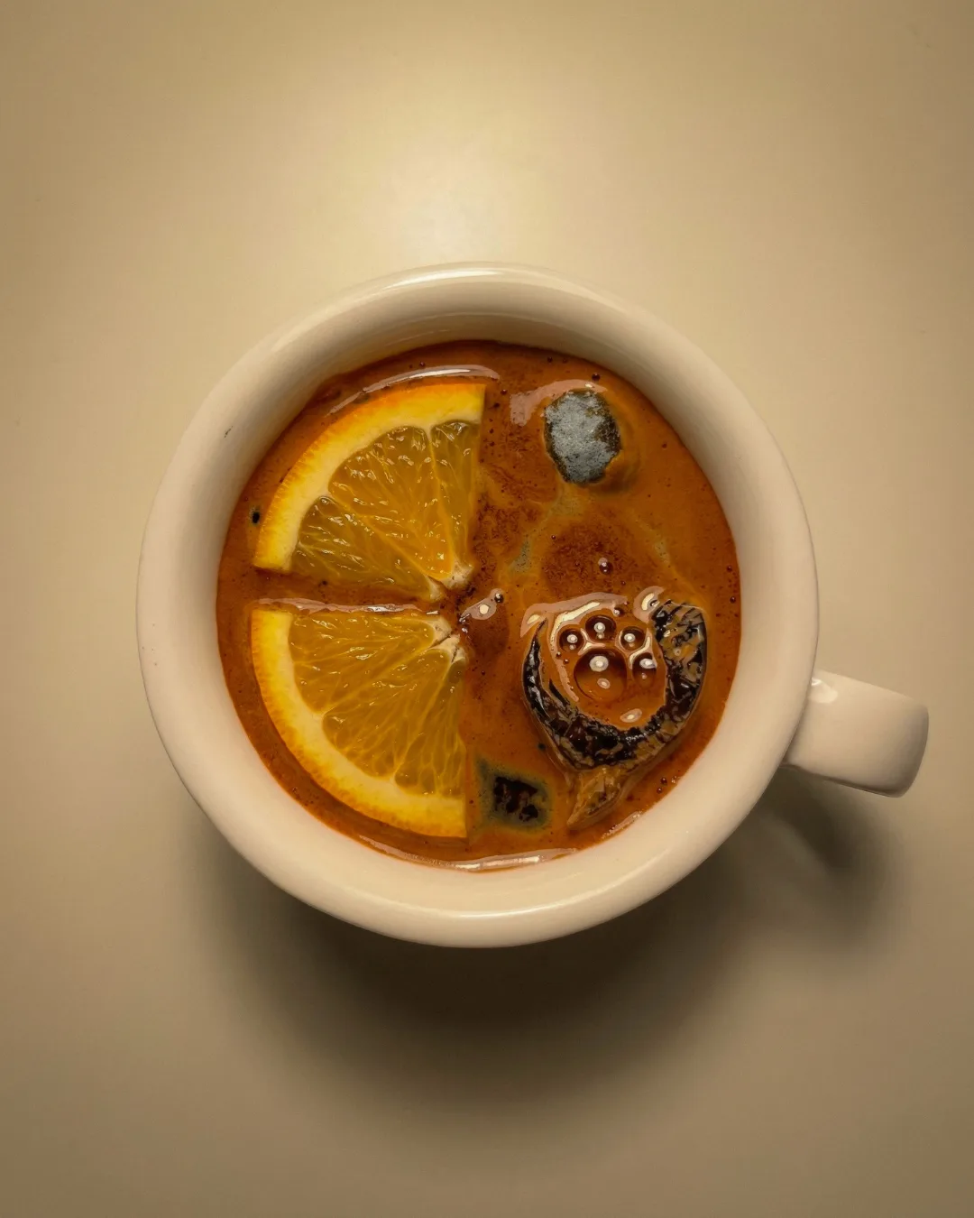 Surreale Tasse mit orangefarbener Flüssigkeit und Zitrusfrüchten