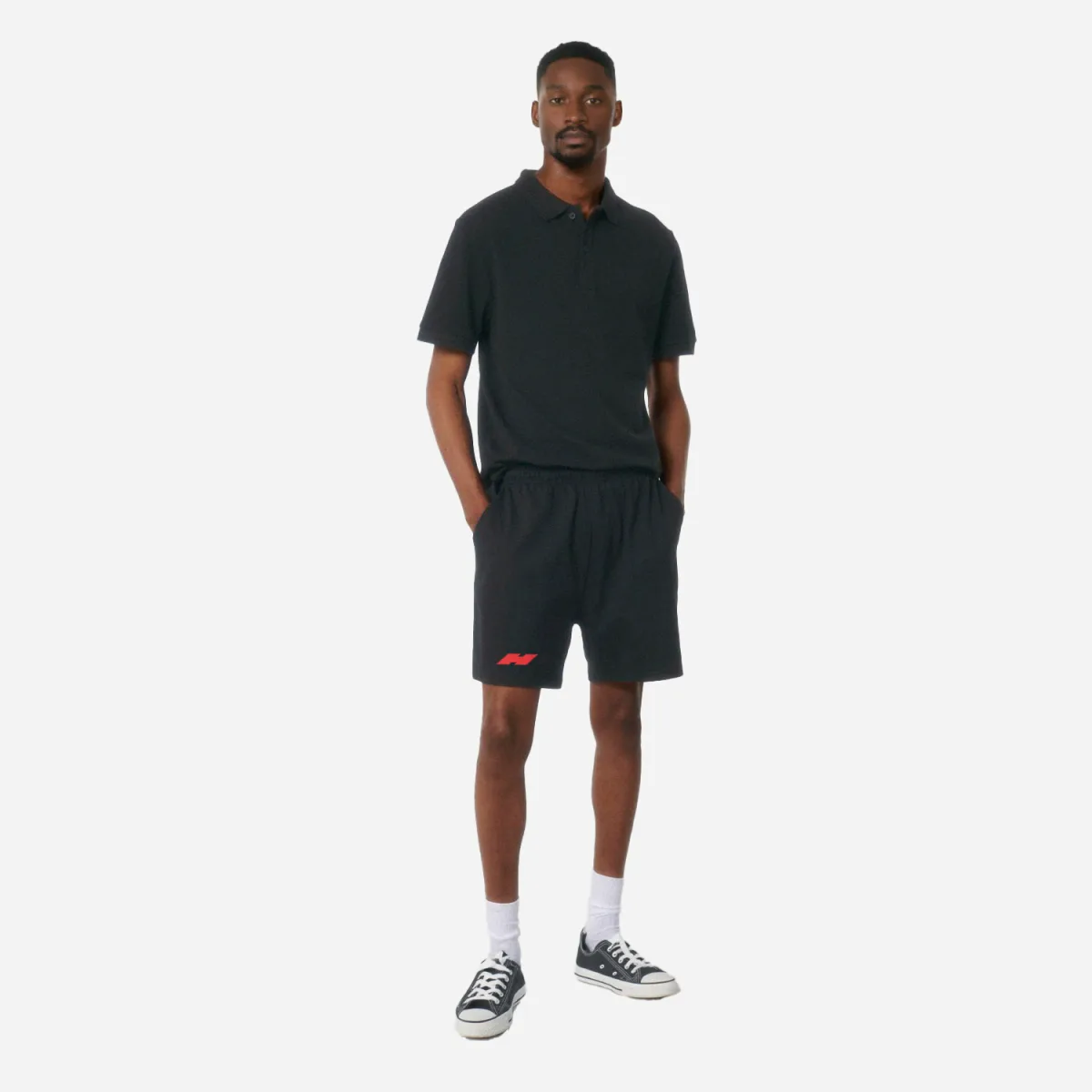 Model in schwarzem Outfit mit rotem hided Markenzeichen auf der Shorts